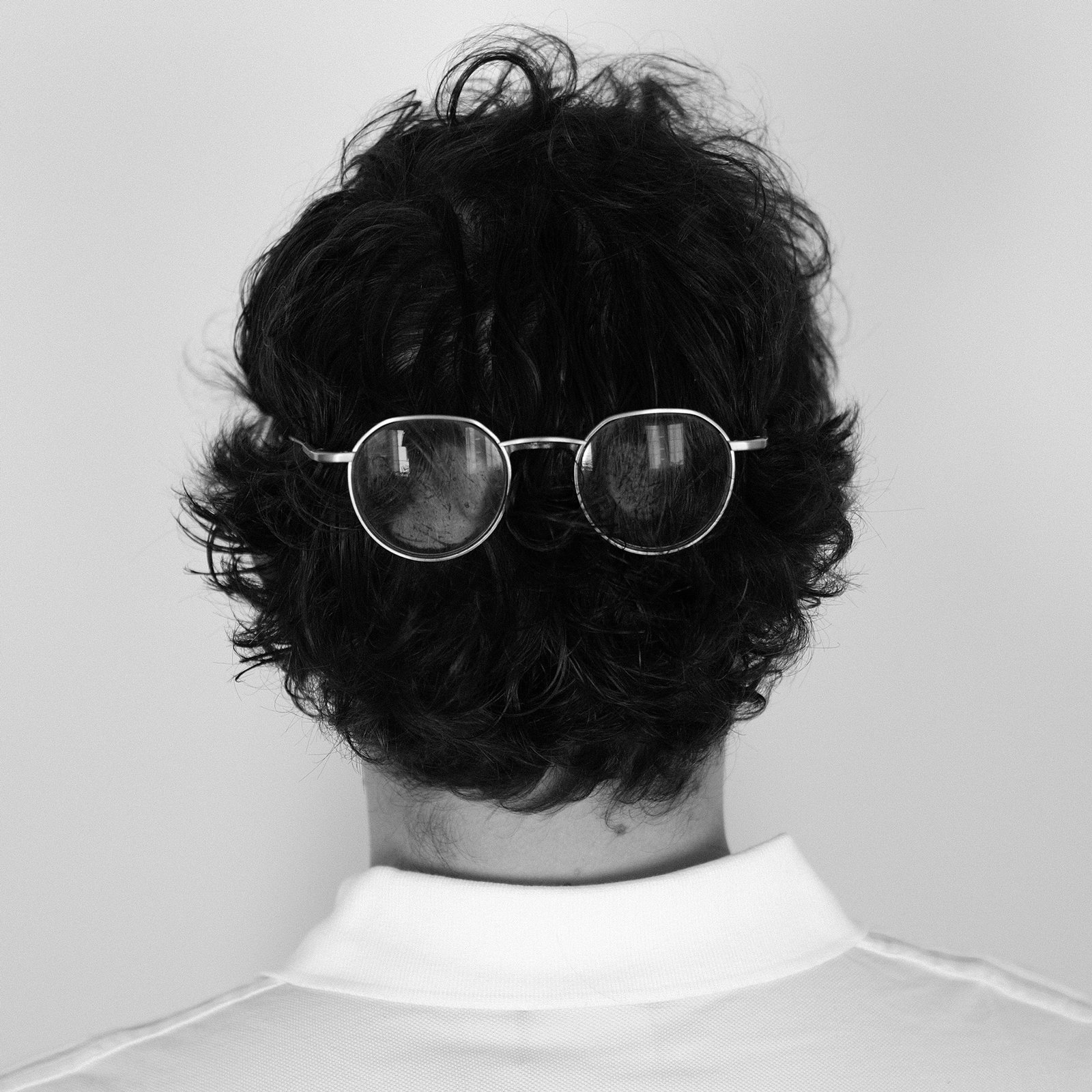 alix videlier design studio 20 Portrait créatif en noir et blanc d’un designer produit à Strasbourg, représentant Alix Videlier Design Studio. L’image montre le dos du sujet avec des lunettes placées sur l’arrière de la tête, soulignant une approche originale et conceptuelle du design.