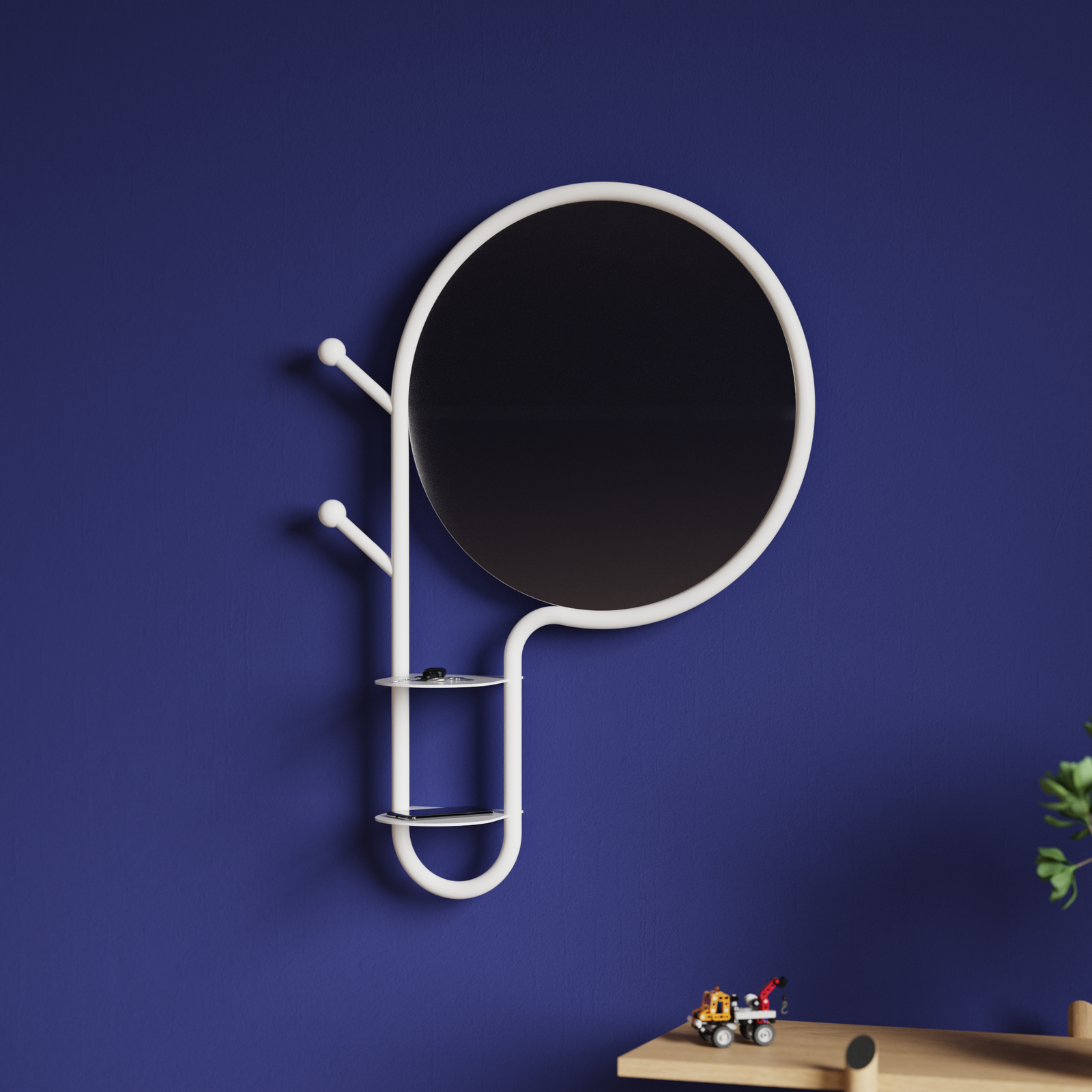 ariane 2 Ariane, miroir mural design avec cadre en tube de métal blanc, intégrant porte-manteaux et vide-poche, idéal pour les entrées. Fabrication française. Design moderne et fonctionnel accroché sur un mur bleu avec étagère en bois en bas à droite.