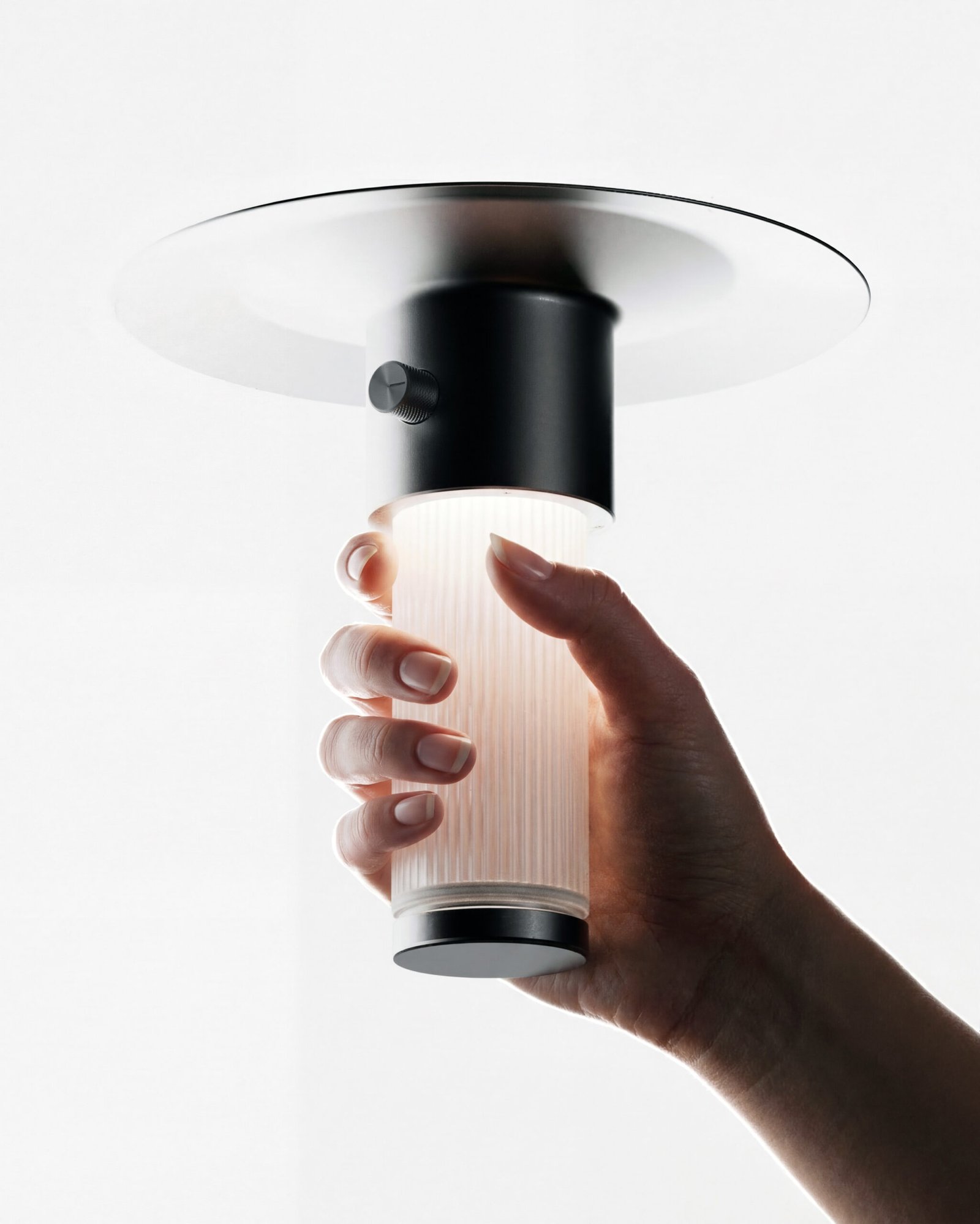 Edwin est une lampe solaire rechargeable conçue par alix videlier design studio à Strasbourg en Alsace. Une main prend la lampe.